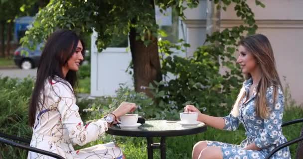 Δύο πανέμορφες γυναίκες κουτσομπολεύουν με ένα φλιτζάνι καφέ. - Πλάνα, βίντεο