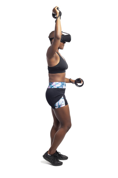 Athletic black female playing a vr video game pretending to do mountain climbing in virtual reality.  She is gaming while exercising to depict technology and healthy activities.  - Zdjęcie, obraz
