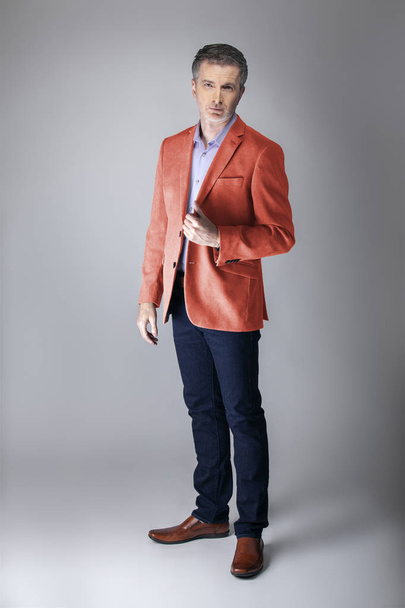 Middle-aged fashion model wearing coral colored sports coat or jacket for the fall clothing collection.  Depicts modern colorful apparel style for 2019.  - Photo, image