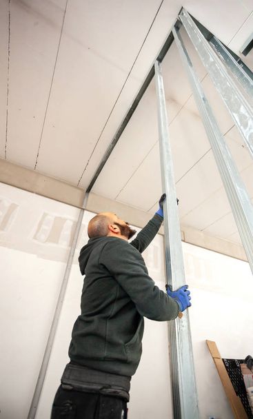 Trabajador construye una pared de cartón yeso
. - Foto, Imagen