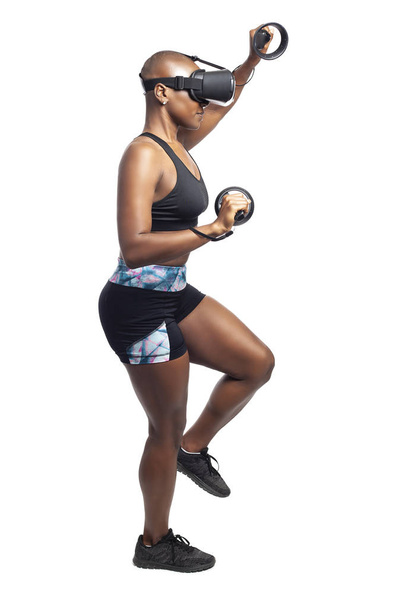 バーチャルリアリティで登山をするふりをするVRビデオゲームをプレイするアスレチック黒人女性。彼女は技術と健康的な活動を描くために運動しながら、ゲームです.  - 写真・画像