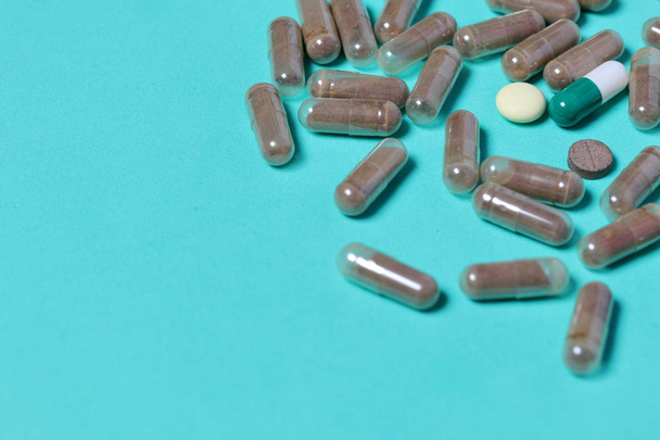 Gelatin pills and tablets of different colors. Medicines scattered on the background of mint color. - Foto, imagen