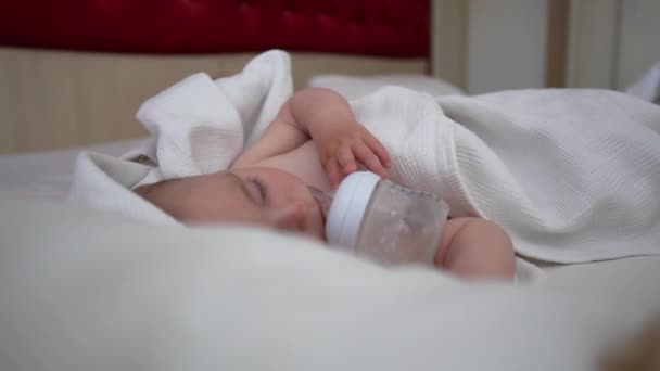 The small baby sweetly sleeps with a bottle near his mouth, slow motion - Materiaali, video