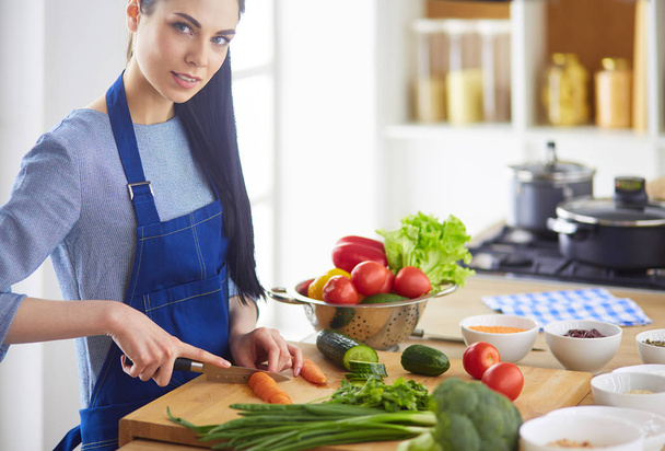 Young woman cutting vegetables in kitchen at home - Foto, Imagen