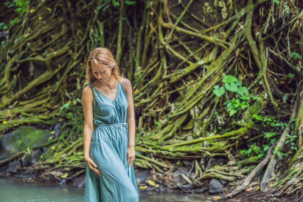 Young woman traveler in a Balinese garden overgrown with moss. Travel to Bali concept - Foto, afbeelding
