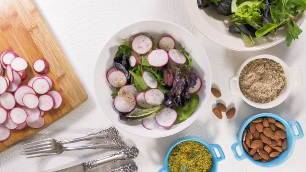  Mélanger la salade d'herbes avec des légumes frais biologiques, de l'huile végétale, des amandes et un peu d'assaisonnement
 - Photo, image