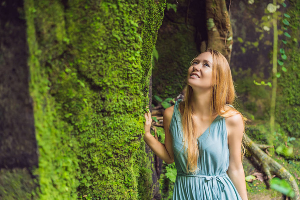 Young woman traveler in a Balinese garden overgrown with moss. Travel to Bali concept - Fotoğraf, Görsel