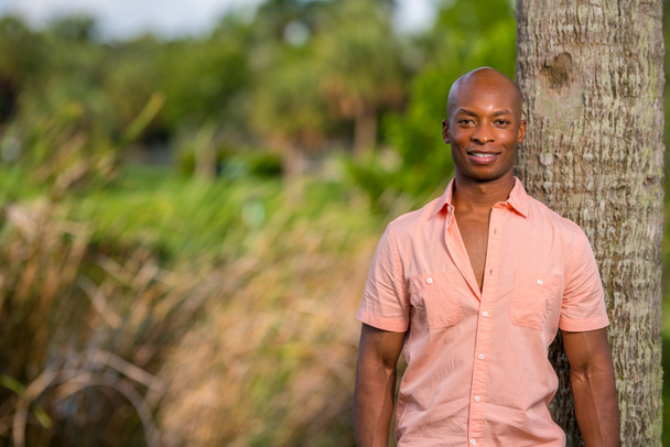 ピンクのボタンでポーズハンサムなアフリカ系アメリカ人の男性モデル - 写真・画像