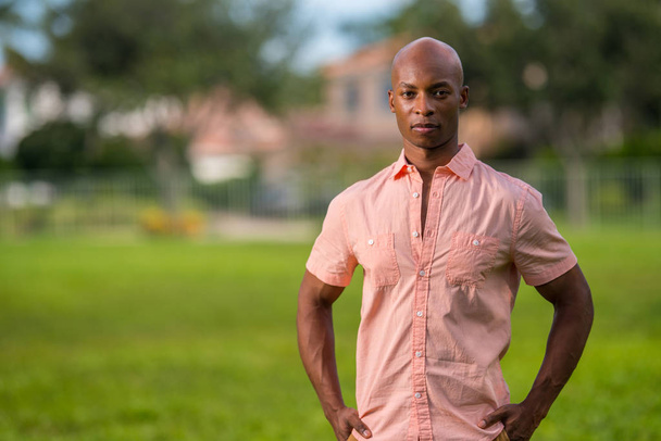 African American man posing in a pink shirt in an ourdoors park  - Photo, Image