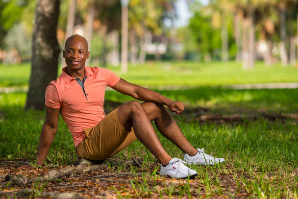 Atraktivní mladý afroamerický mužský model sedící v parku - Fotografie, Obrázek