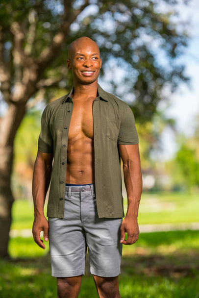 Сексуальная мужская модель позирует в парке в расстегнутой рубашке
 - Фото, изображение
