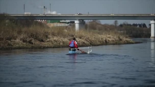 Uomo disabile che rema sul fiume in canoa. Canottaggio, canoa, canoa. Allenamento. Kayak. sport paraolimpico. Ponte sullo sfondo
. - Filmati, video
