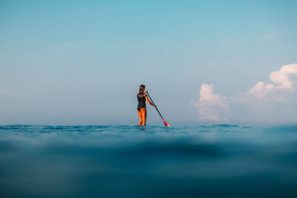 12 Απριλίου, 2019. Μπαλί, Ινδονησία. Όρθια κουπί κορίτσι σέρφινγκ στον ωκεανό. Μπαλί-Όρθια Κωπηλασία surf - Φωτογραφία, εικόνα