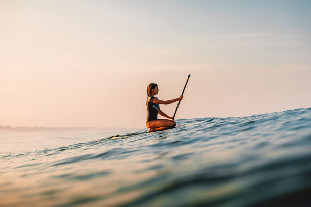 12. huhtikuuta 2019. Balilla, Indonesiassa. Stand Up Meloa surffata tyttö meressä. Stand Up Mela surffailu Balilla
 - Valokuva, kuva