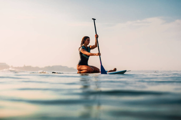 12 квітня 2019. Балі, Індонезія. Встати весло серфінгу дівчина в океані. Встати весло серфінг в Балі - Фото, зображення