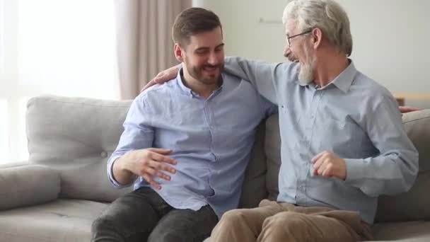 Happy old father laughing embracing young son giving fist bump - Filmagem, Vídeo