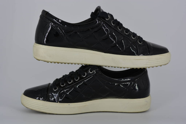 Youth black patent leather shoes, sneakers with a thick white sole and black laces. Stylish and elegant shoes with an interesting style and material located on a white background. - Photo, Image