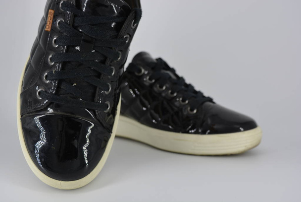 Μαύρο δερμάτινα παπούτσια για τη νεολαία, αθλητικά παπούτσια με παχιά λευκή σόλα και μαύρα κορδόνια. Κομψά και κομψά παπούτσια με ένα ενδιαφέρον στυλ και υλικό που βρίσκεται σε λευκό φόντο. - Φωτογραφία, εικόνα