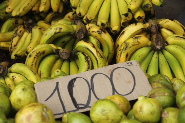Bananes tropicales et goyaves avec tableau des prix sur le marché
. - Photo, image