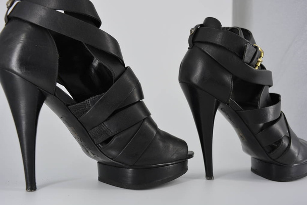 Sandales sexy pour femmes noires glamour en cuir de vache mat sur talons hauts. Chaussures de mode pour femmes en bandes de cuir, rubans avec fermoir doré dessus
. - Photo, image