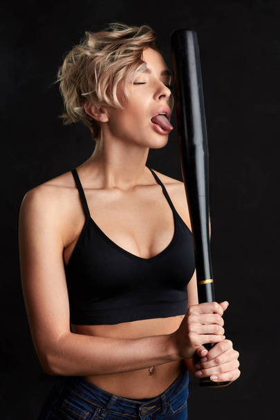 mad carzy girl hsowing her tongue while holding a bat - Photo, Image