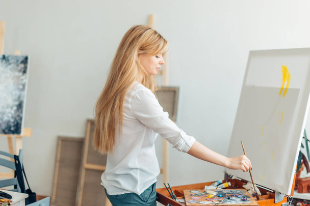 fair-haired woman painting with a brush - Fotó, kép