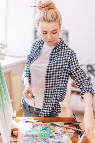 fair-haired woman choosing tool for painting - Photo, image