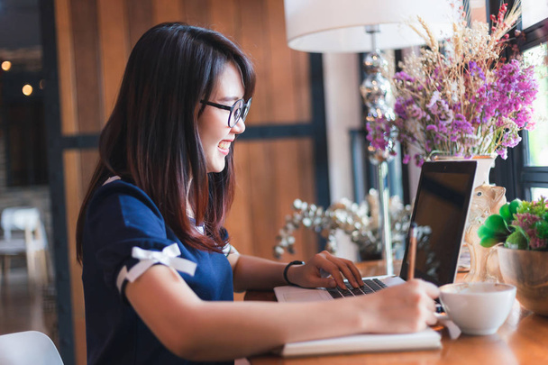 Asiática mulher de negócios trabalhando com laptop fazer uma nota no café como o fundo
. - Foto, Imagem