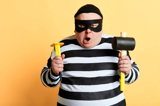 angry plump criminal in striped clothes preparing for crime - Фото, изображение