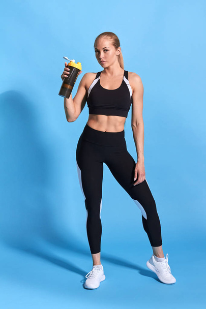 sexy fit sportswoman holding water and looking at the camera - Photo, image