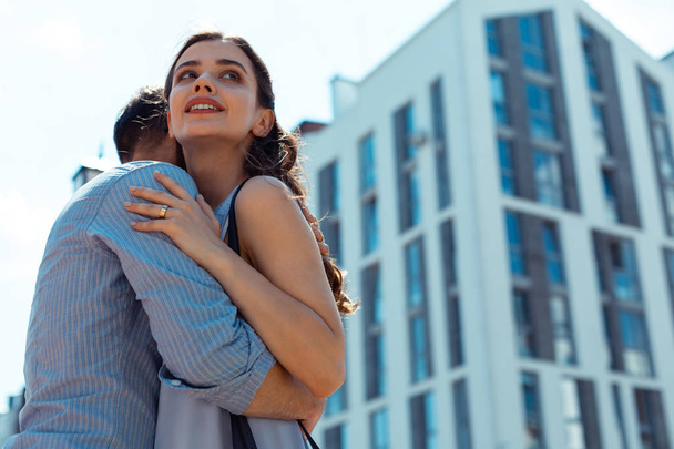 Dark-haired wife hugging her man wearing striped shirt - Foto, immagini