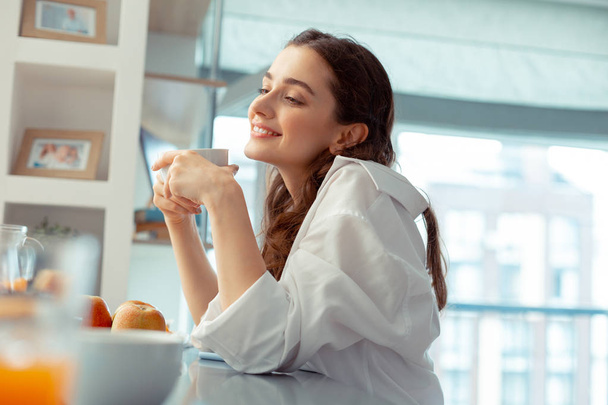 Woman wearing white shirt feeling relaxed drinking coffee - Fotografie, Obrázek
