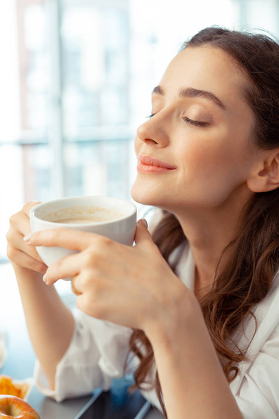 Woman enjoying the smell of freshly brewed coffee - Фото, изображение