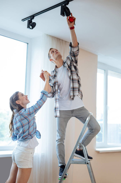 Husband changing the light bulb while moving with wife - 写真・画像