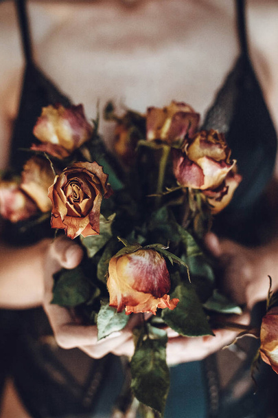 Vrouw het houden van boeket van gedroogde rozen. Caducity of Beauty concept. - Foto, afbeelding