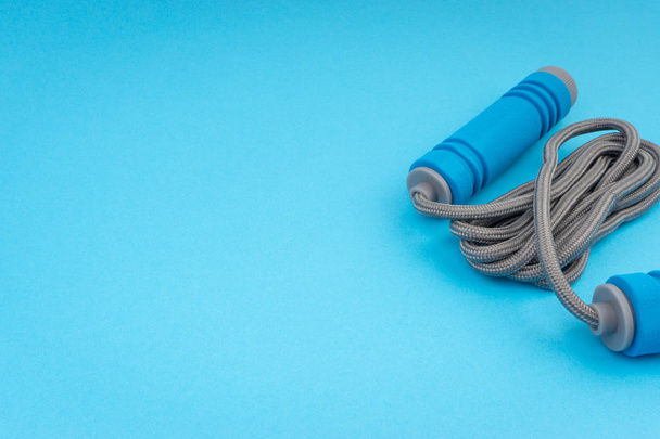 Corde à sauter ou corde à sauter isolée sur fond bleu. Concentration sélective et fragment de culture
 - Photo, image