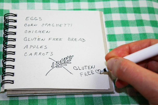 Geen gluten dieet boodschappenlijstje met een hand, die het schrijven van de inscriptie glutenvrij - Foto, afbeelding