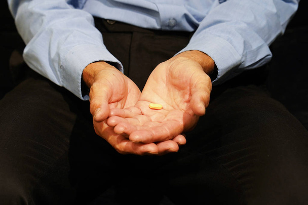 Elderly man holding a pill in hand - Photo, Image