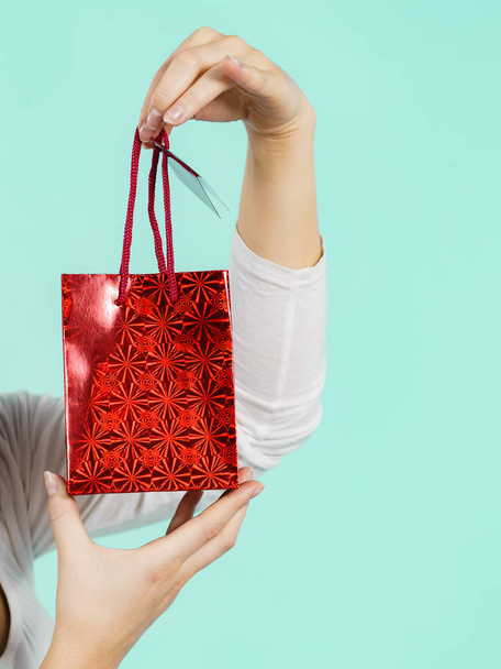 Woman holds red gift bag in hand - Φωτογραφία, εικόνα