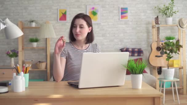 Young woman looking for information on the Internet in a laptop and holding a hearing aid - Video, Çekim