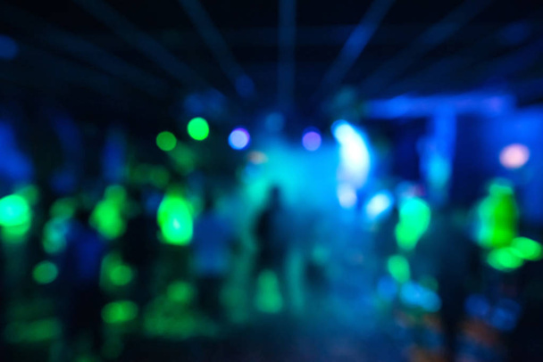 blurred silhouettes of a group of people dancing in a nightclub on the dance floor under colorful spotlights - Photo, Image