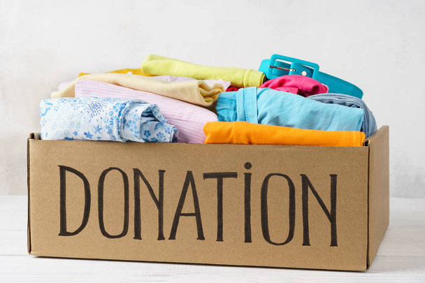 Donation box with various clothes on a table. - Фото, зображення