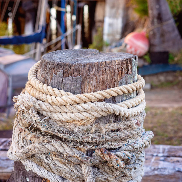 Oude houten paal verpakt in Fraying touw - Foto, afbeelding
