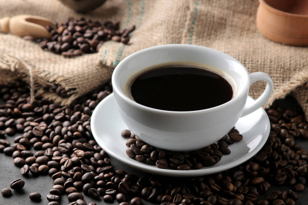 Pörkölt kávésszemek és egy csésze kávét egy barna fa háttér. Attila, akác. - Fotó, kép