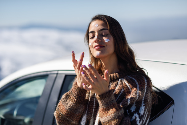 Nuori nainen soveltamalla aurinkovoidetta hänen kasvonsa lumi maisema
 - Valokuva, kuva