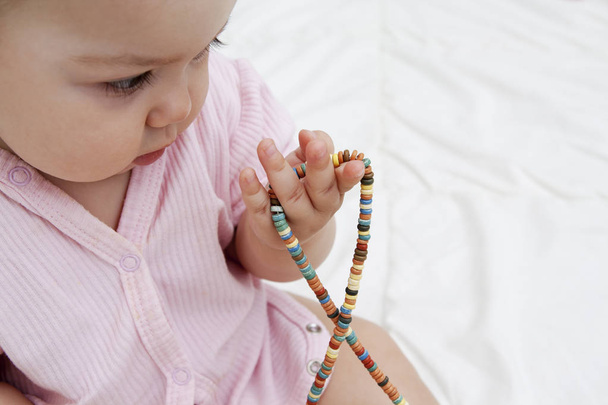 Farbige Perlen in den Händen eines Säuglings - die Entwicklung der Flosse - Foto, Bild