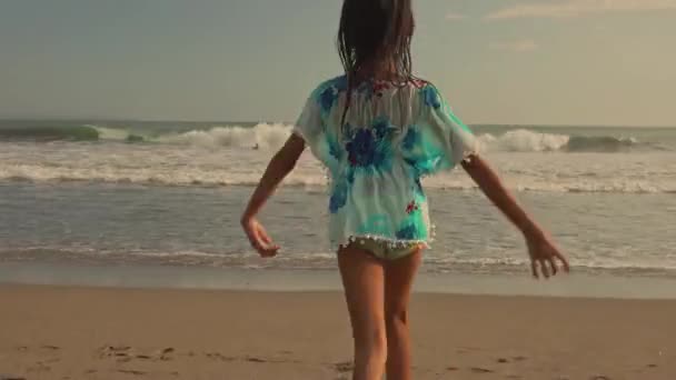 Gimbal стезікамера відстеження послідовність 8 або 9 років красивою і щасливою азіатських Індонезійська дитина дівчина працює безтурботним на пляжі веселяться насолоджуючись літні канікули на захід сонця на екзотичному острові - Кадри, відео