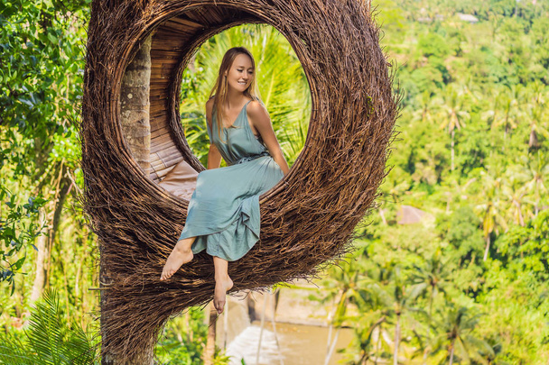 Bali trend, straw nests everywhere. Young tourist enjoying her travel around Bali island, Indonesia. Making a stop on a beautiful hill. Photo in a straw nest, natural environment. Lifestyle - Zdjęcie, obraz