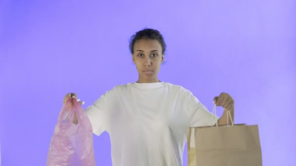 Afro-American Girl Activist κάνοντας μια επιλογή μεταξύ χαρτιού και πλαστικής τσάντας σε φόντο Violet - Πλάνα, βίντεο