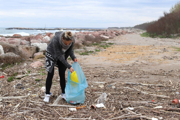 Giovane ragazza raccogliendo spazzatura dalla spiaggia
. - Foto, immagini